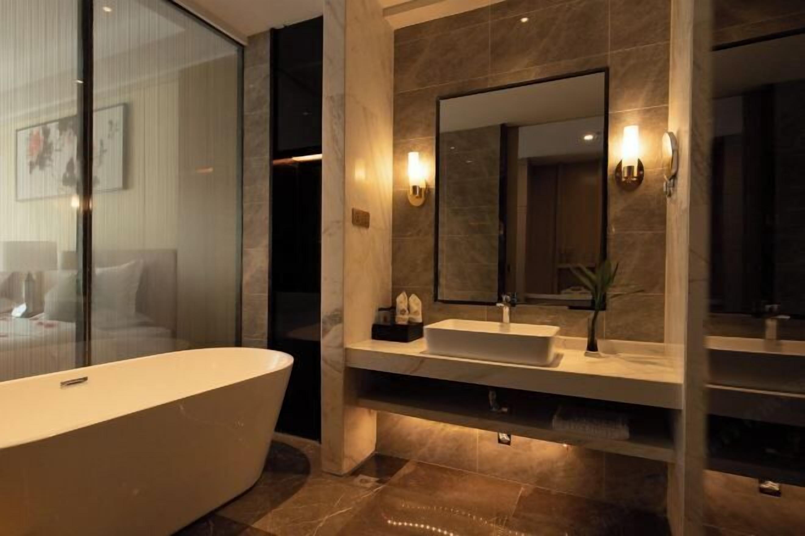 A modern bathroom with a freestanding bathtub, a large mirror, and a vanity with a sink.