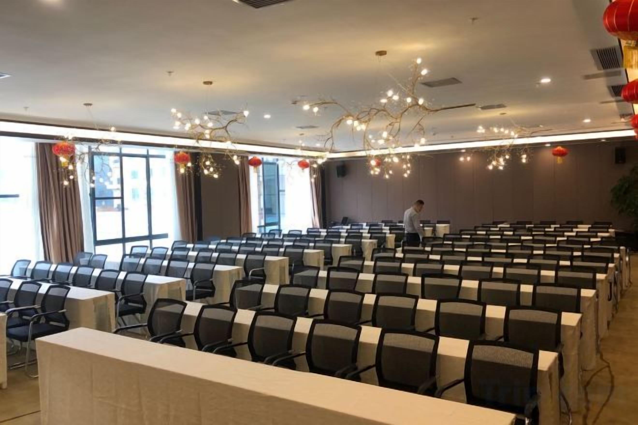 A conference room with rows of chairs, a long table, and a person standing near the back wall.
