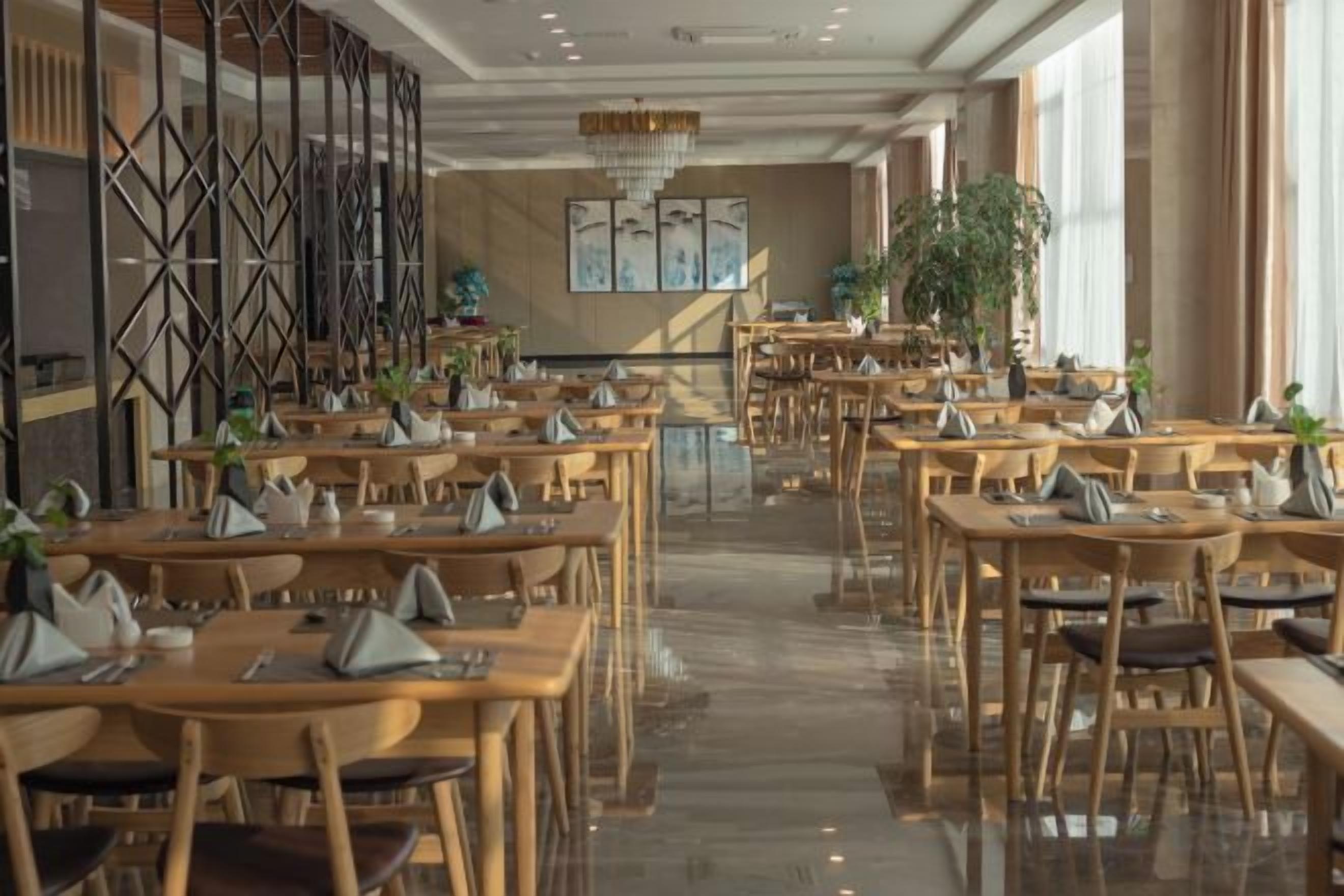 Un comedor amplio con varias mesas y sillas, una escalera central y paneles decorativos en las paredes.