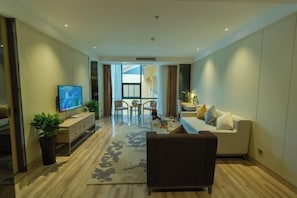 A modern living room with a flat-screen TV, a sofa, a coffee table, and a potted plant.