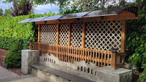 Uma estrutura tradicional japonesa em madeira, com telhado inclinado, painel treliçado e base de pedra.