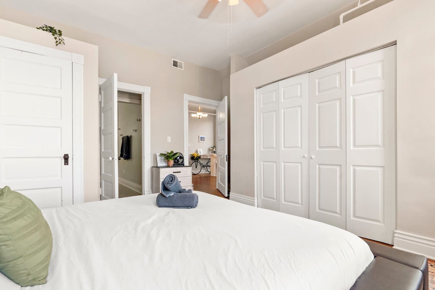 Une chambre à coucher avec un grand lit, des murs blancs et un placard à plusieurs portes.