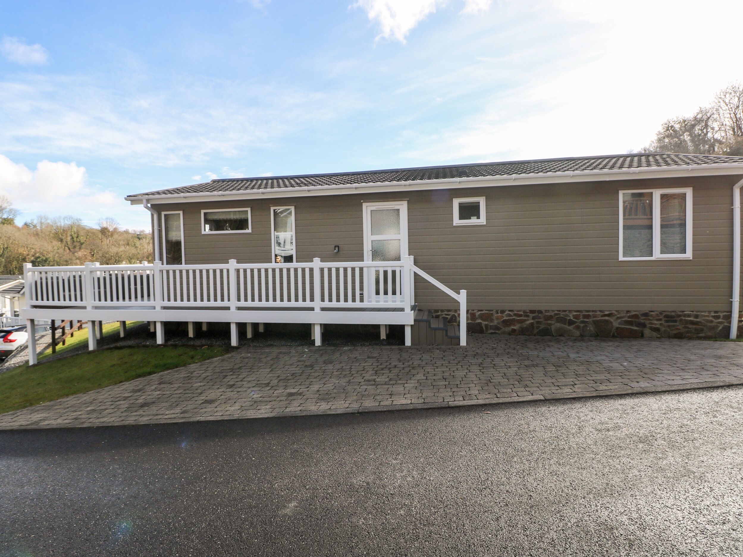 A single-story mobile home with a front porch and a stone foundation.