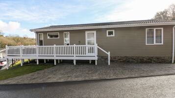 A single-story mobile home with a front porch and a stone foundation.