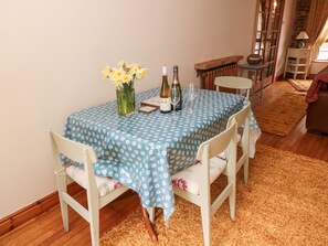 A dining table with a blue tablecloth, two bottles of wine, and a vase of yellow flowers. - Bolland Hall (Morpeth)