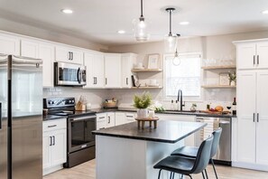 A modern kitchen with white cabinets, stainless steel appliances, and a central island with bar stools.
