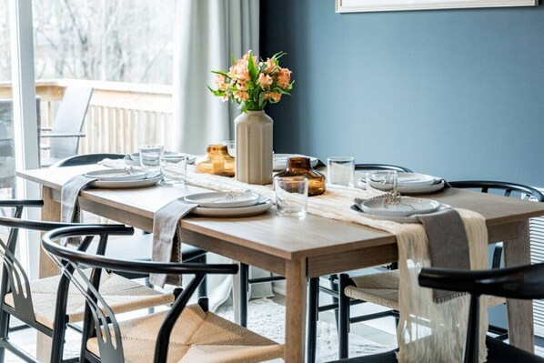 A dining table set with plates, glasses, and a vase of flowers.
