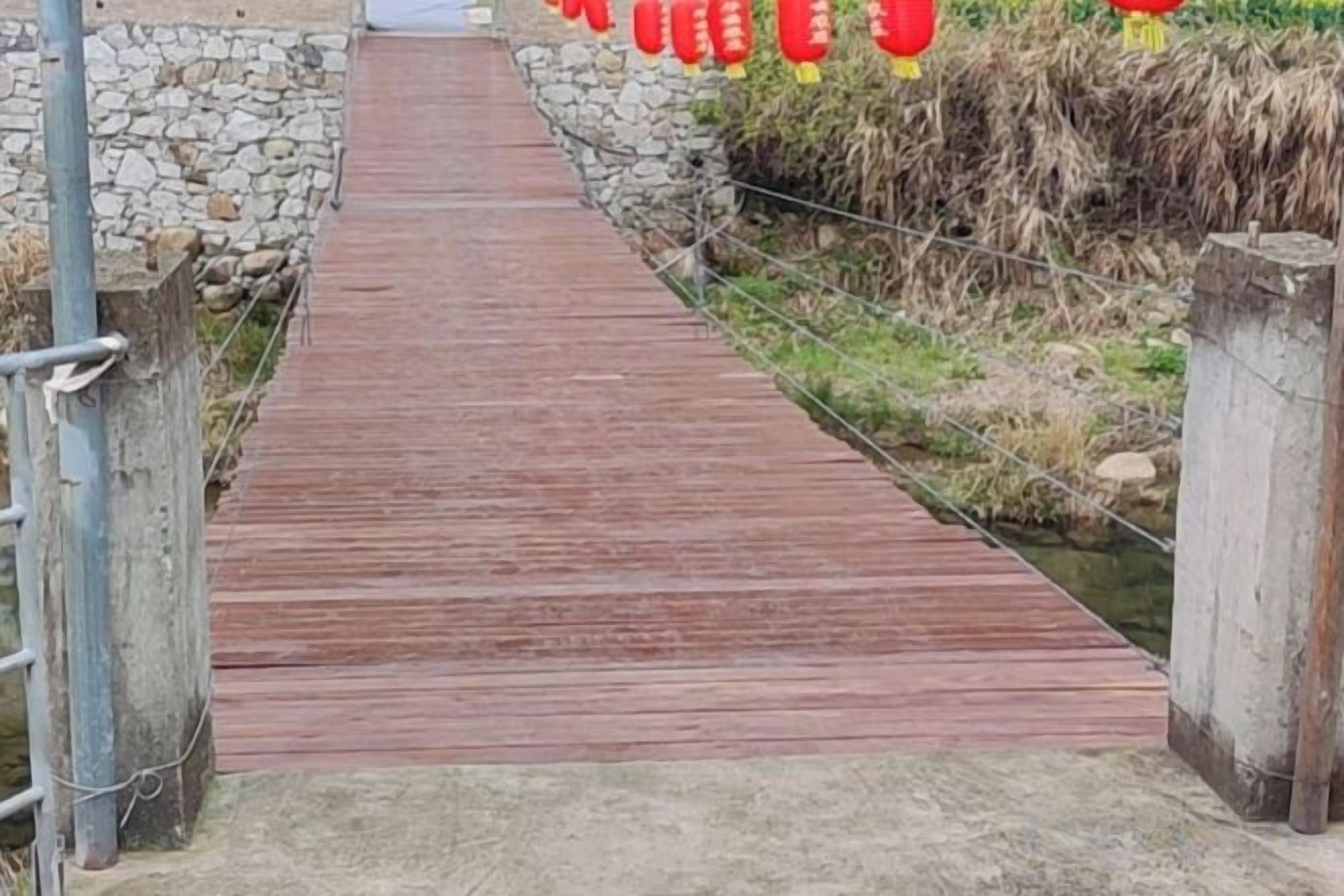Een houten pad dat naar een gebouw met stenen muren leidt.