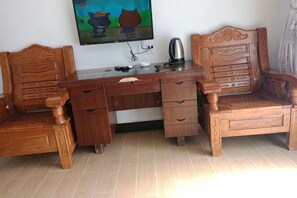 A wooden desk with drawers, a chair, a television mounted on the wall, and a kettle. - Wuyuan Jiangling Huayun Hotel (Wuyuan)
