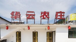 Un edificio con un letrero que dice “华云农庄” y tres puertas con diseños tradicionales chinos.