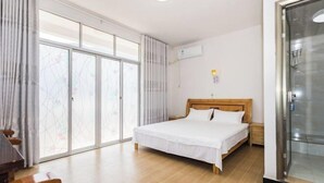 Un dormitorio con una cama de madera, una puerta corrediza de vidrio, una mesita de noche pequeña y un aire acondicionado instalado en la pared.