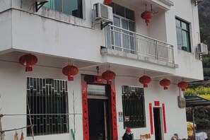 A two-story building with a balcony, red lanterns, and a sign with Chinese characters.