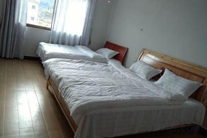 Una habitación con dos camas individuales, un cabecero de madera y una ventana con cortinas.