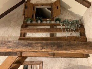 A wooden staircase with a mirror above, surrounded by potted plants.