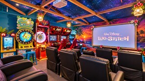 Sala com máquinas de jogos, tela de projeção e assentos.