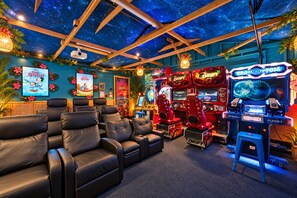 A room with a starry ceiling, gaming machines, and plush seating. - Underwater Voyage: Heated Pool, Slide, Arcade, more! (Garden Grove)