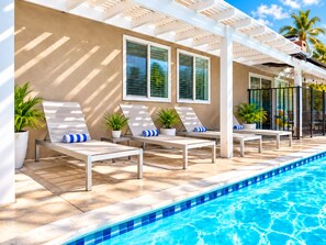 A poolside area with lounge chairs and potted plants. - Underwater Voyage: Heated Pool, Slide, Arcade, more! (Garden Grove)