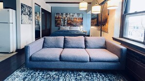 Un salon moderne avec un canapé gris, un tapis à motifs et des œuvres d’art accrochées aux murs.