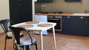 A compact kitchen with dark cabinets, a white table, and two chairs.