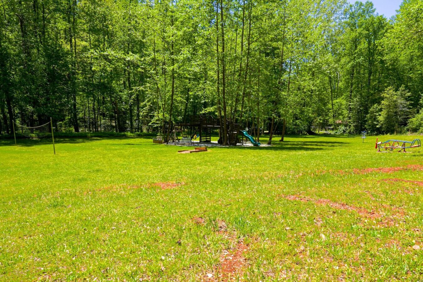 A park with a playground, open grassy areas, and dense trees.