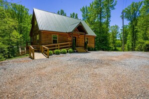 Une cabane en bois avec un toit en métal, une véranda et une allée gravillonnée.