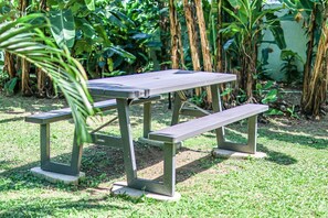 A picnic table with benches in a garden area.