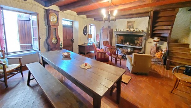 Ein rustikaler Essbereich mit Holztisch und Bänken, einem Kamin und traditioneller Einrichtung.