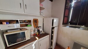 Eine kompakte Küche mit weißen Schränken, einer Mikrowelle, einem Kühlschrank und einer Holz Arbeitsplatte.