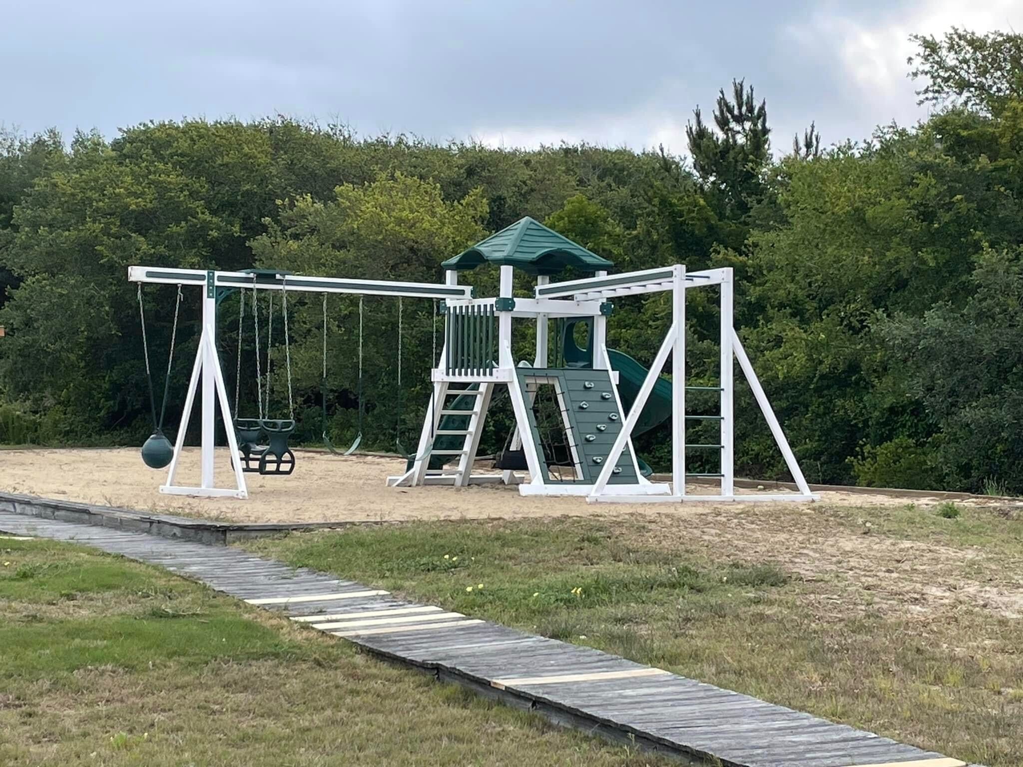 A playground with swings, a slide, and a climbing structure.