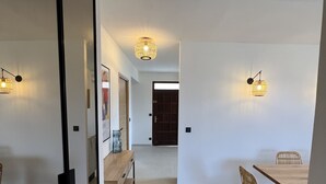 A modern interior with a dining area, a wooden bench, and two wall-mounted lights. - Magnificent pool villa with sea, lake and mountain views (Santa reparata di balagna)