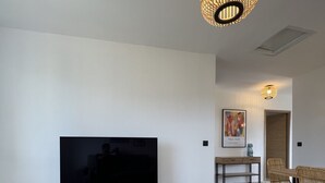A modern living room with a flat-screen TV, wooden furniture, and a unique light fixture. - Magnificent pool villa with sea, lake and mountain views (Santa reparata di balagna)