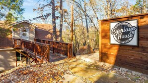 A wooden cabin with a deck and a sign that reads "Carriage House."