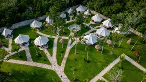 Une vue aérienne d’un complexe hôtelier avec de nombreuses tentes en forme de dôme disposées en cercle, entourées de pelouses bien entretenues et de sentiers.