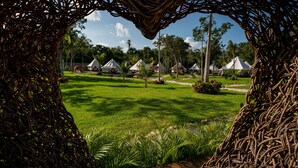 Vue d’un complexe hôtelier avec des bungalows aux toits de chaume et une pelouse bien entretenue.