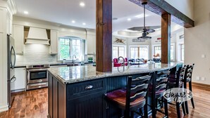 A spacious kitchen with a large island, wooden beams, and modern appliances. - 6 bed 4 bath cottage on Lake Muskoka, Private, Boathouse, Hot tub! (Gravenhurst)