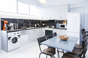 Enjoy meals and casual gatherings at the dining table with washing machine and compact refrigerator nearby.