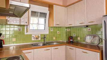 A compact kitchen with a window, green tiled backsplash, and a stove.