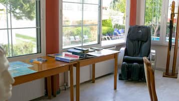 Una habitación con un ventanal grande, un escritorio de madera con libros, una silla y un radiador.