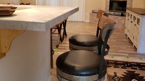 A kitchen with a bar area, two stools, a ceiling fan, and a fireplace. - Beautiful custom home w pool & garage! Perfect snowbird retreat, close to all! (Lake Havasu City)