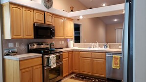 A modern kitchen with wooden cabinets, stainless steel appliances, and a patterned rug. - Beautiful custom home w pool & garage! Perfect snowbird retreat, close to all! (Lake Havasu City)