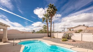 A swimming pool with clear blue water, surrounded by a concrete deck and palm trees. - Beautiful custom home w pool & garage! Perfect snowbird retreat, close to all! (Lake Havasu City)