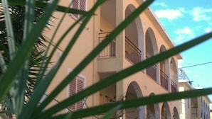 A building with multiple balconies and arches, surrounded by greenery. - Roda Pearl Resort (Corfu)