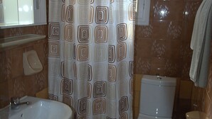 A bathroom with a sink, toilet, and shower curtain. - Roda Pearl Resort (Corfu)