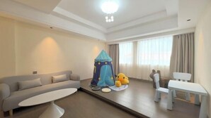 A modern living room with a sofa, a small table, a play tent, and a couple of chairs. - Shunde Yufeng Hotel (Foshan)