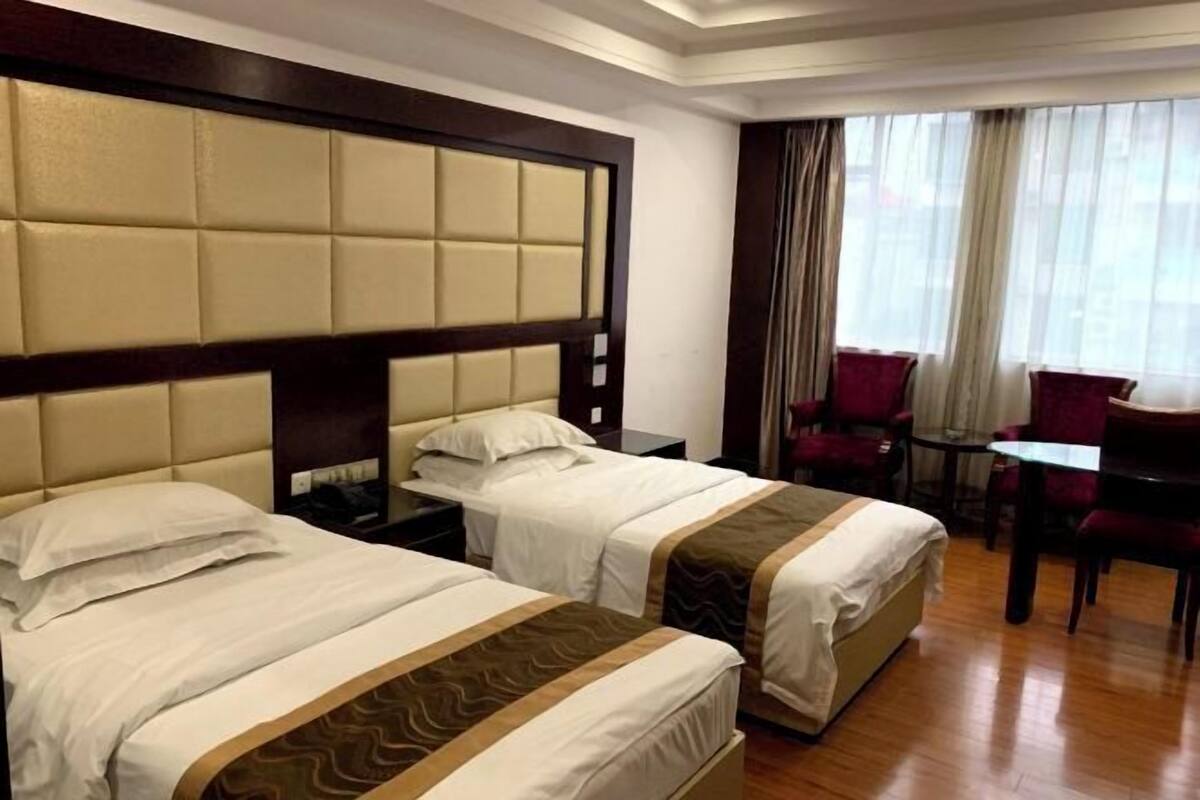 A hotel room with two beds, a dining table, and a chair.
