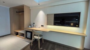 A modern room with a built-in desk, a chair, a TV mounted on the wall, and a wardrobe. - Shunde Yufeng Hotel (Foshan)