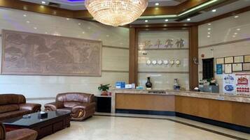 A hotel lobby with a reception desk, seating area, and a chandelier.