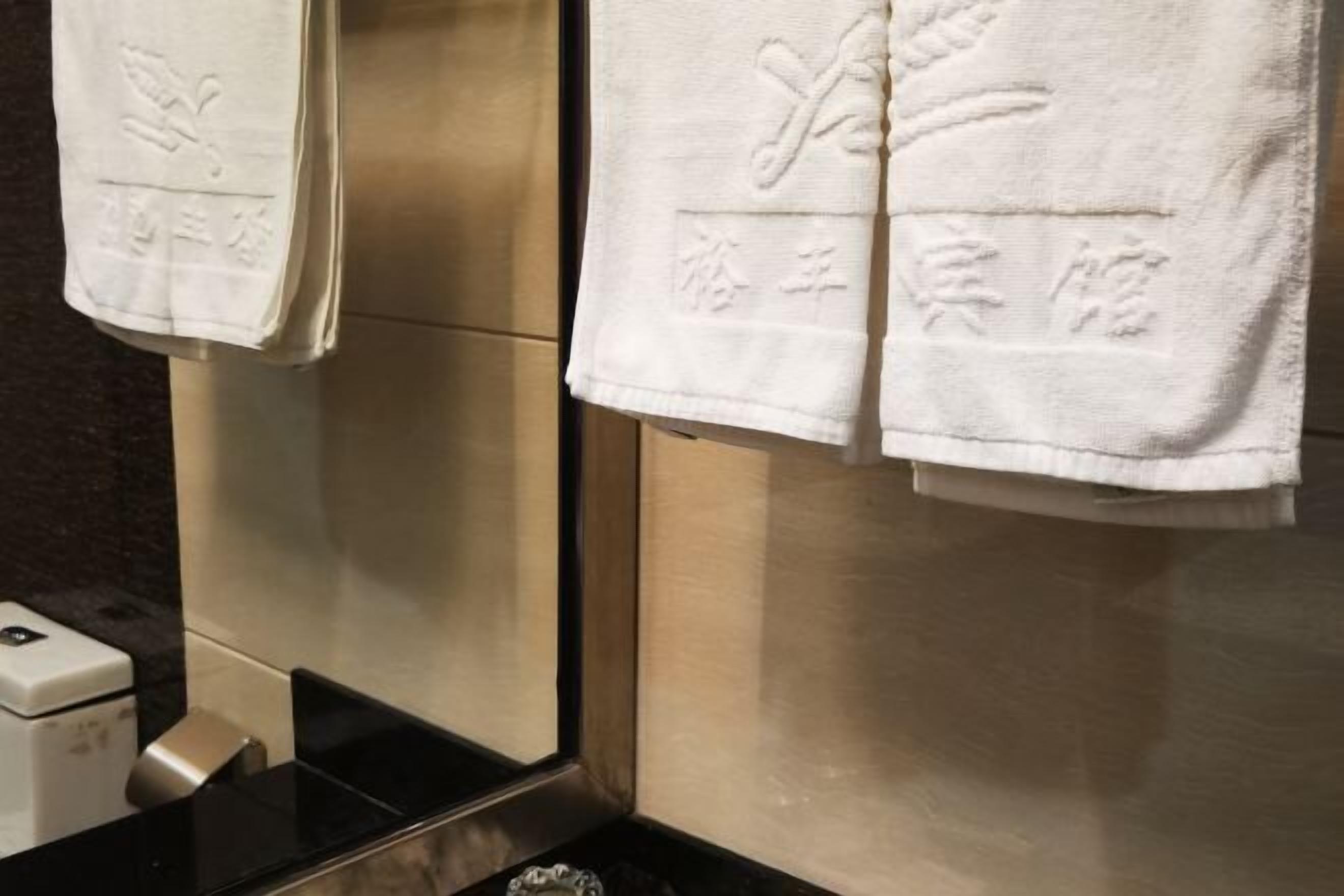 A bathroom with a towel rack holding two white towels with embossed text.