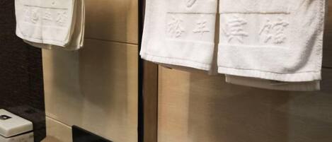A bathroom with a towel rack holding two white towels with embossed text.