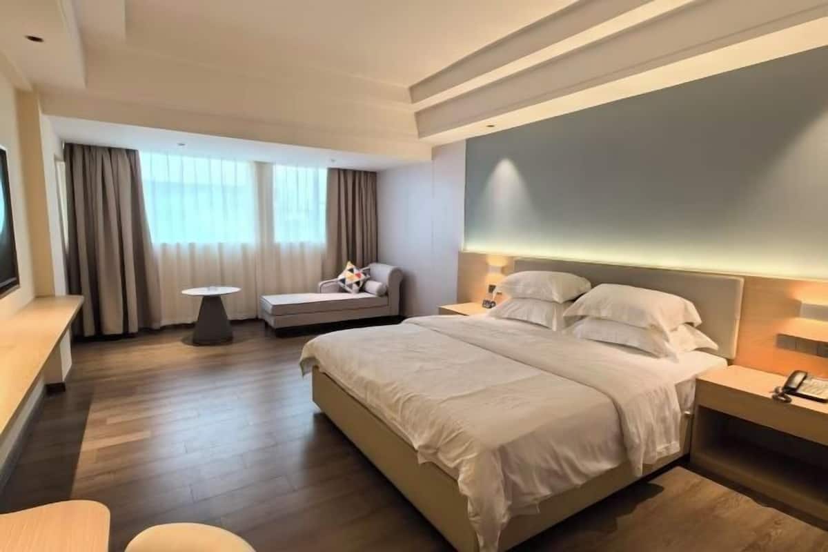A modern hotel room with a large bed, a sofa, a small table, and a TV.